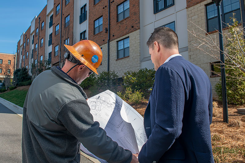 two people looking at blueprints and a building
