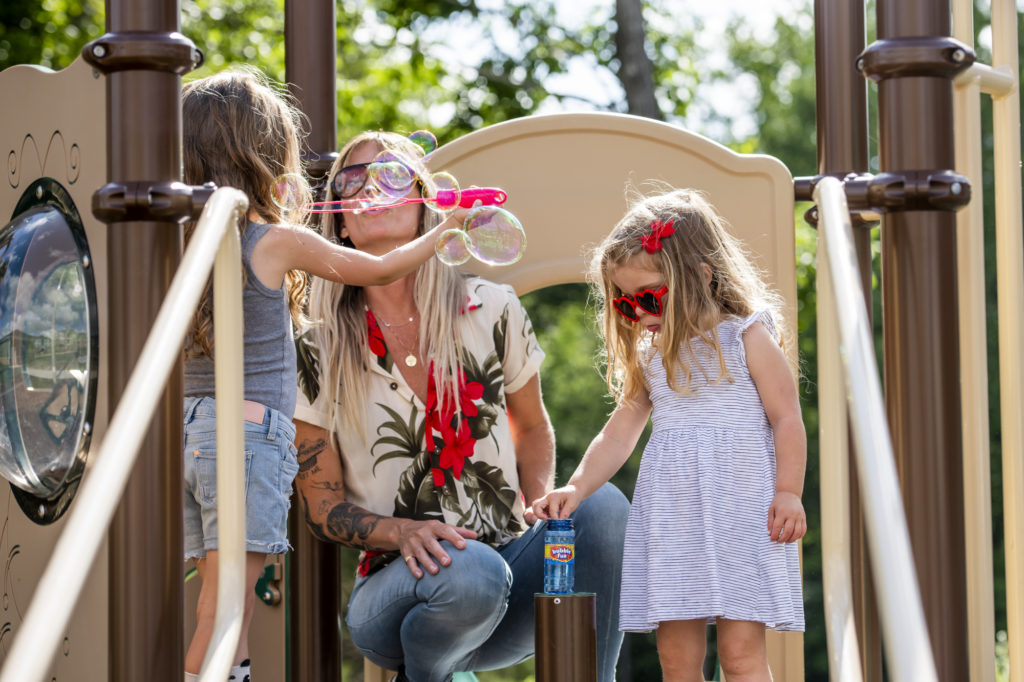 woman with kids blowing bubbles on playground
