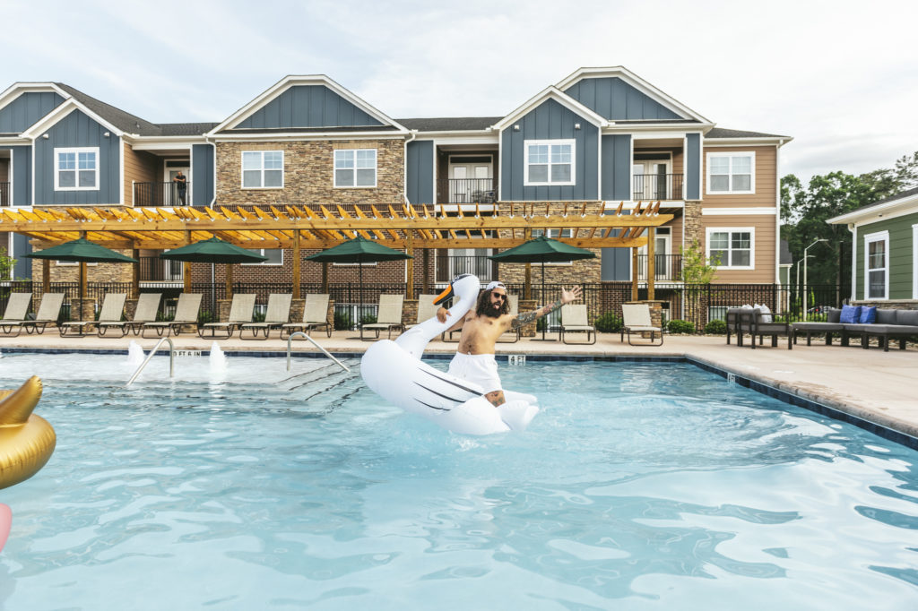 guy on swan float in pool at evolve community